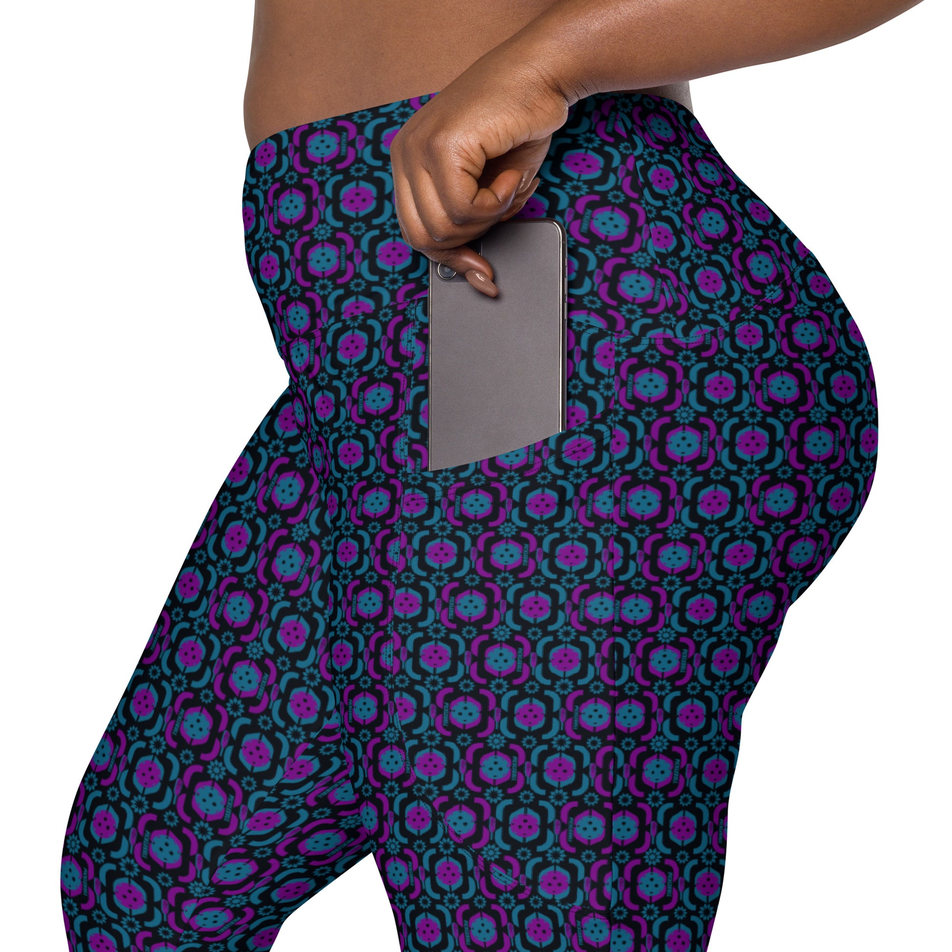 Side view of a person wearing Purple Playmaker Pickleball Leggings, highlighting the side pocket with a hand placing a smartphone inside. The leggings feature a vibrant purple and blue pickleball-themed pattern.